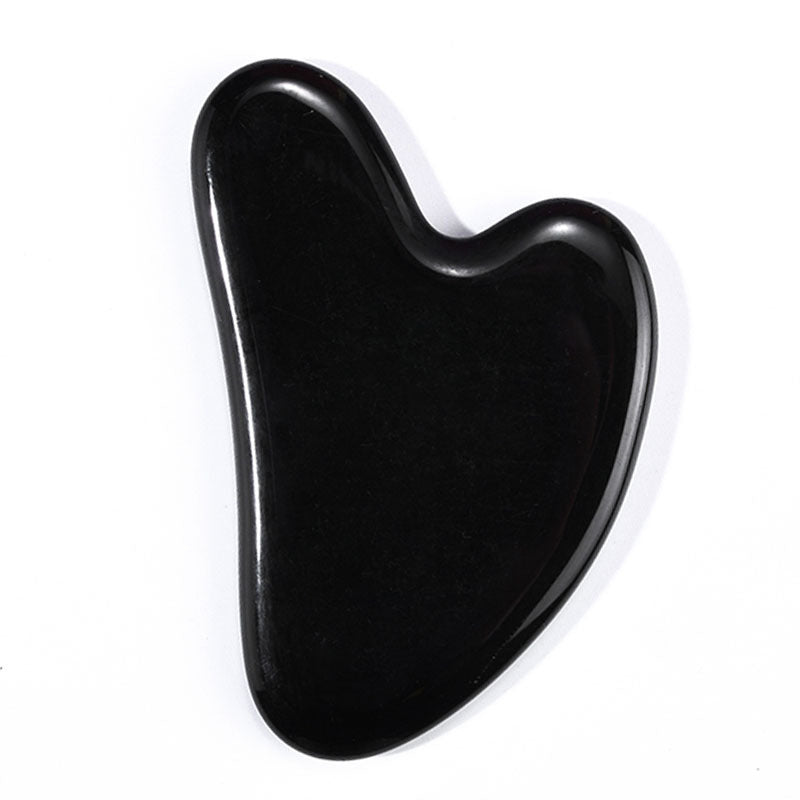 Polished black obsidian gua sha with mirror finish, heart-shaped facial massage tool