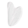 Clear white crystal gua sha stone with glass-smooth polish, heart-shaped facial massage tool