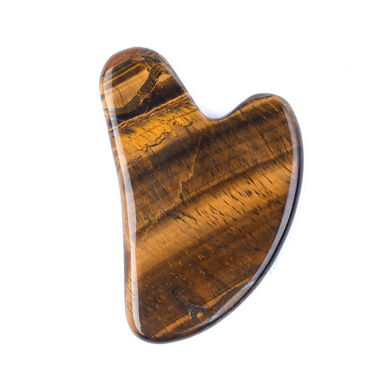 Golden brown tigereye gua sha stone with bands of light, heart-shaped facial massage tool