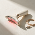 Lyquora LiftWave neck and jaw sculptor with curved steel plate and red LEDs lit, champagne USB-C cable alongside
